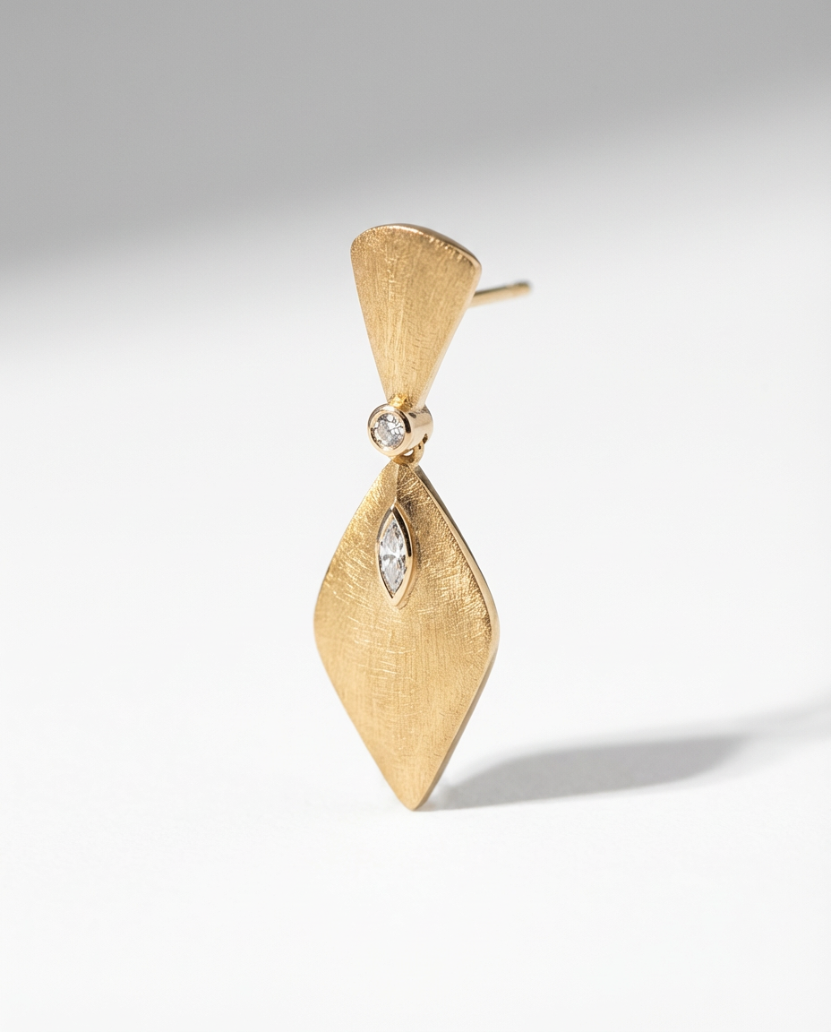 Gold earring with a diamond on a light gray background