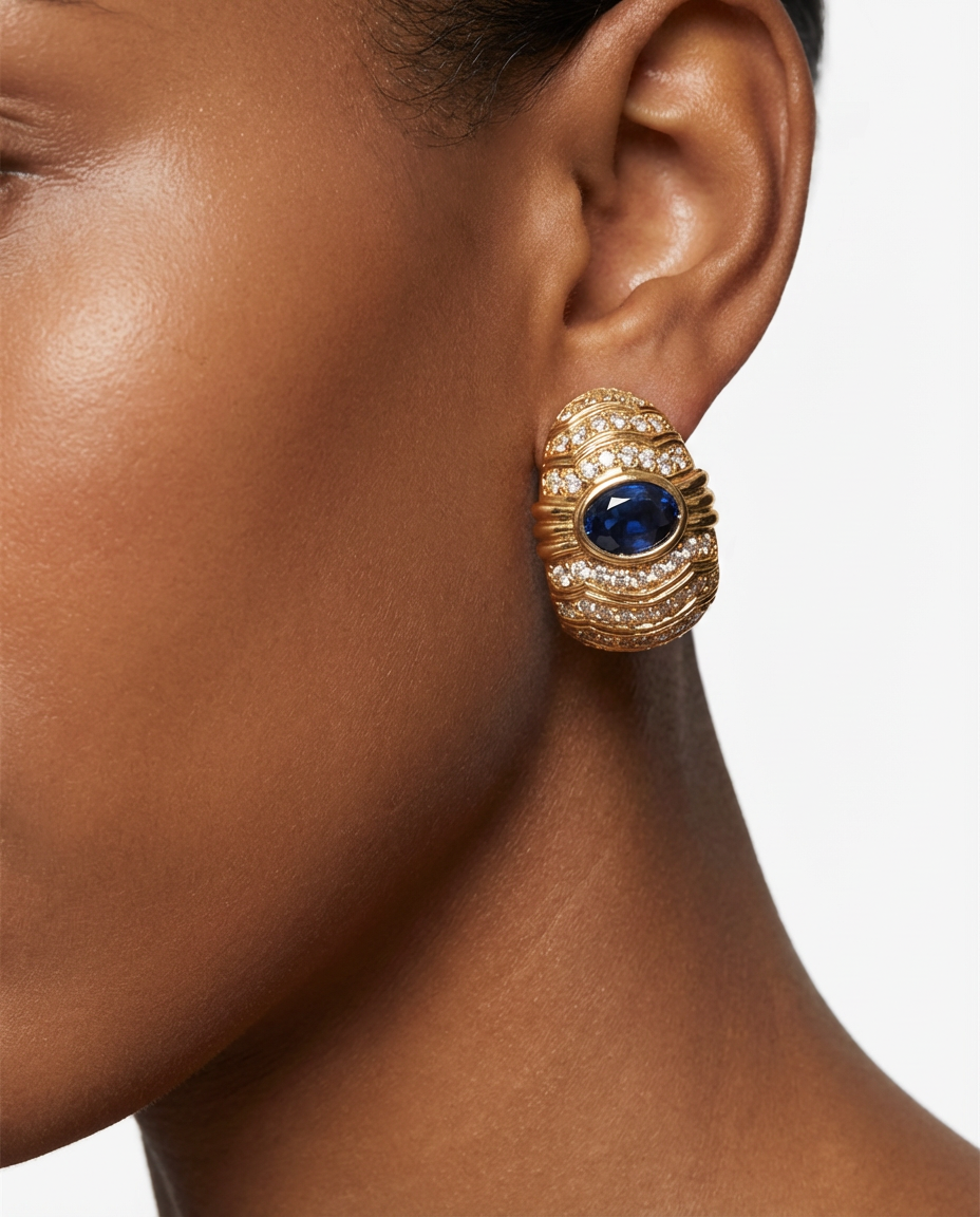 Gold earring with a blue gemstone worn by a model on a white background