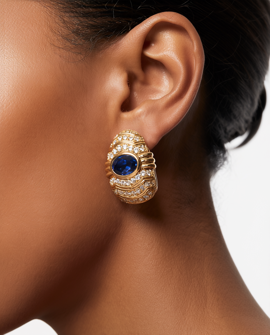 Gold earring with a blue gemstone worn by a person
