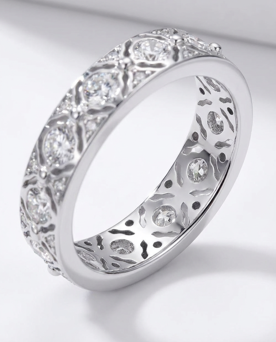Silver ring with intricate design and embedded stones on a light gray background