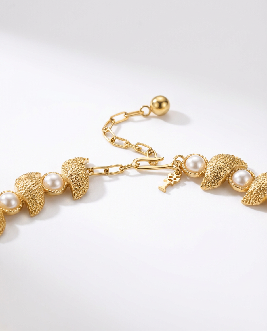 Gold bracelet with leaf and pearl designs on a white background
