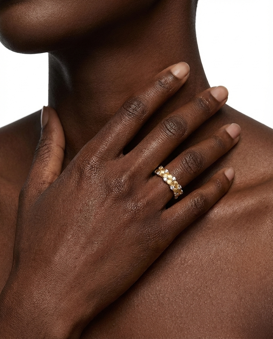 Close-up of a hand wearing a gold ring on a neutral background