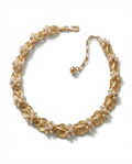 Gold necklace with leaf designs and pearl-like beads on a white background