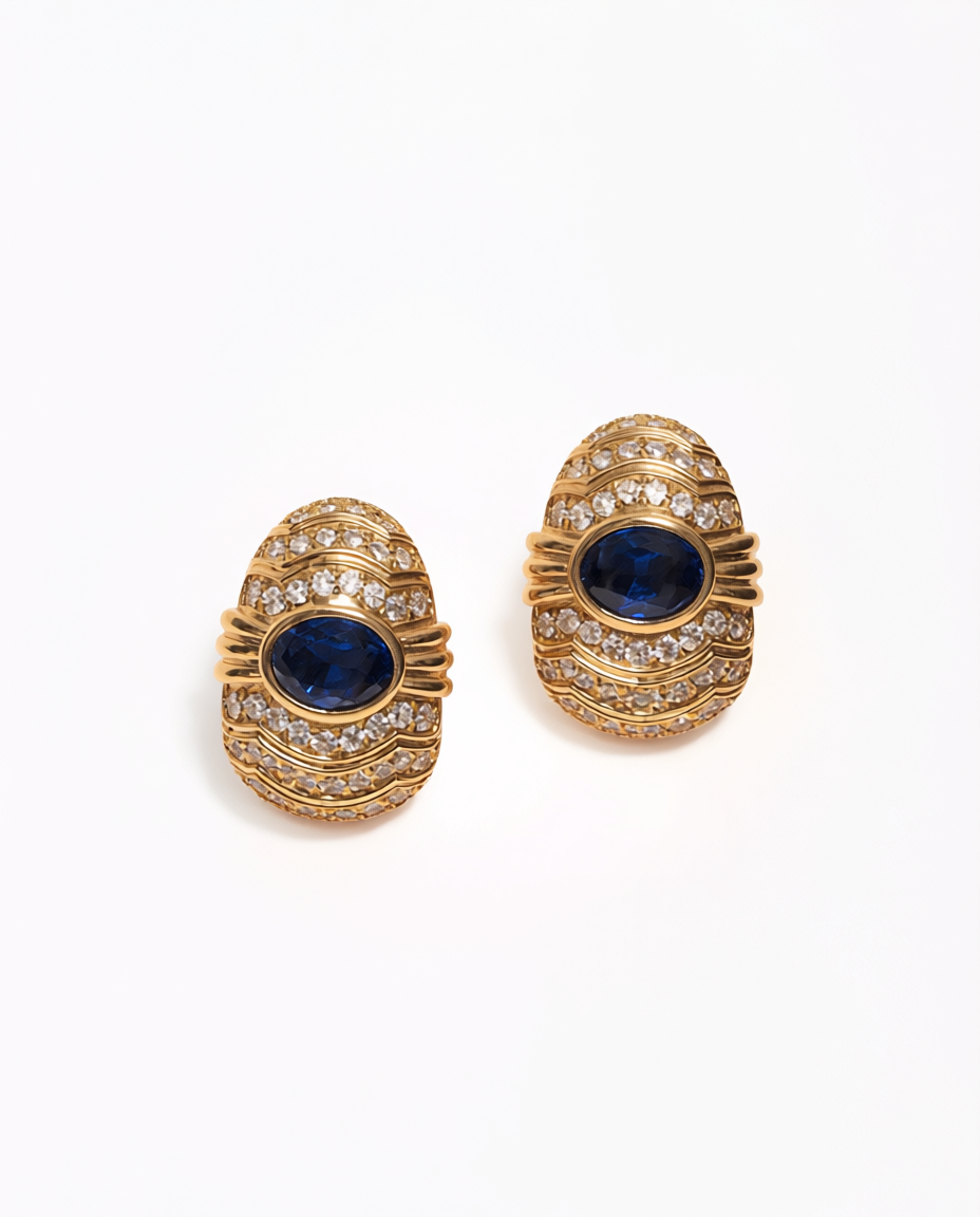 Pair of gold earrings with blue gemstones on a white background