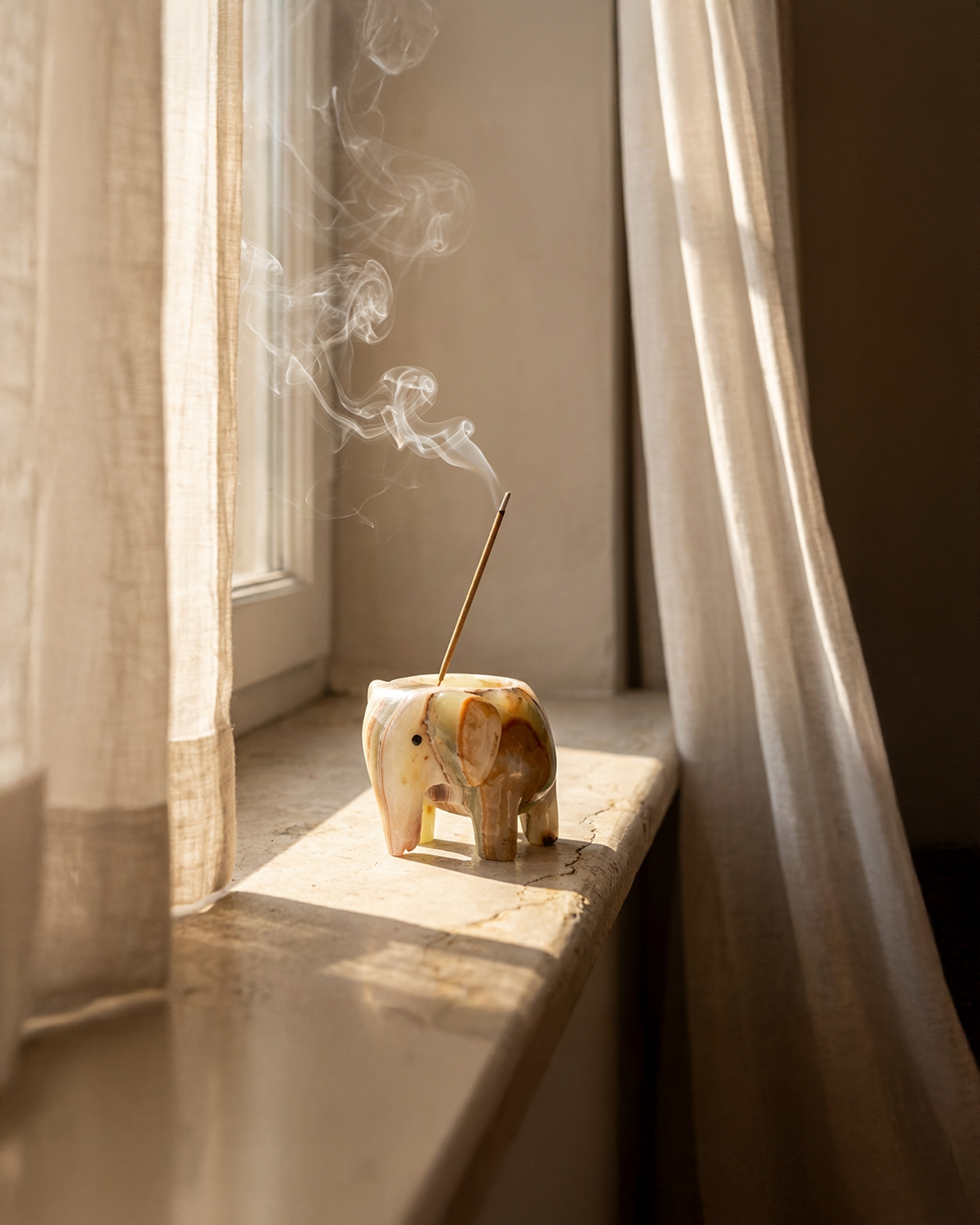 Wooden elephant incense burner with smoke in a softly lit room.