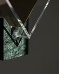 Abstract sculpture with clear acrylic and green marble base on a dark background