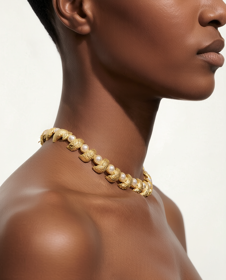 Gold necklace with pearls on a model against a neutral background
