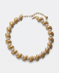 Gold and pearl necklace on a light gray background