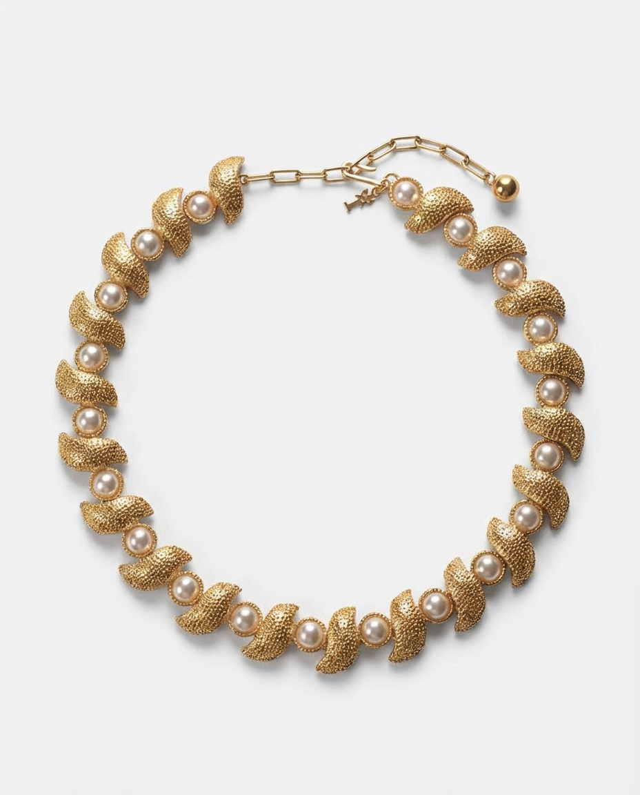 Gold and pearl necklace on a light gray background