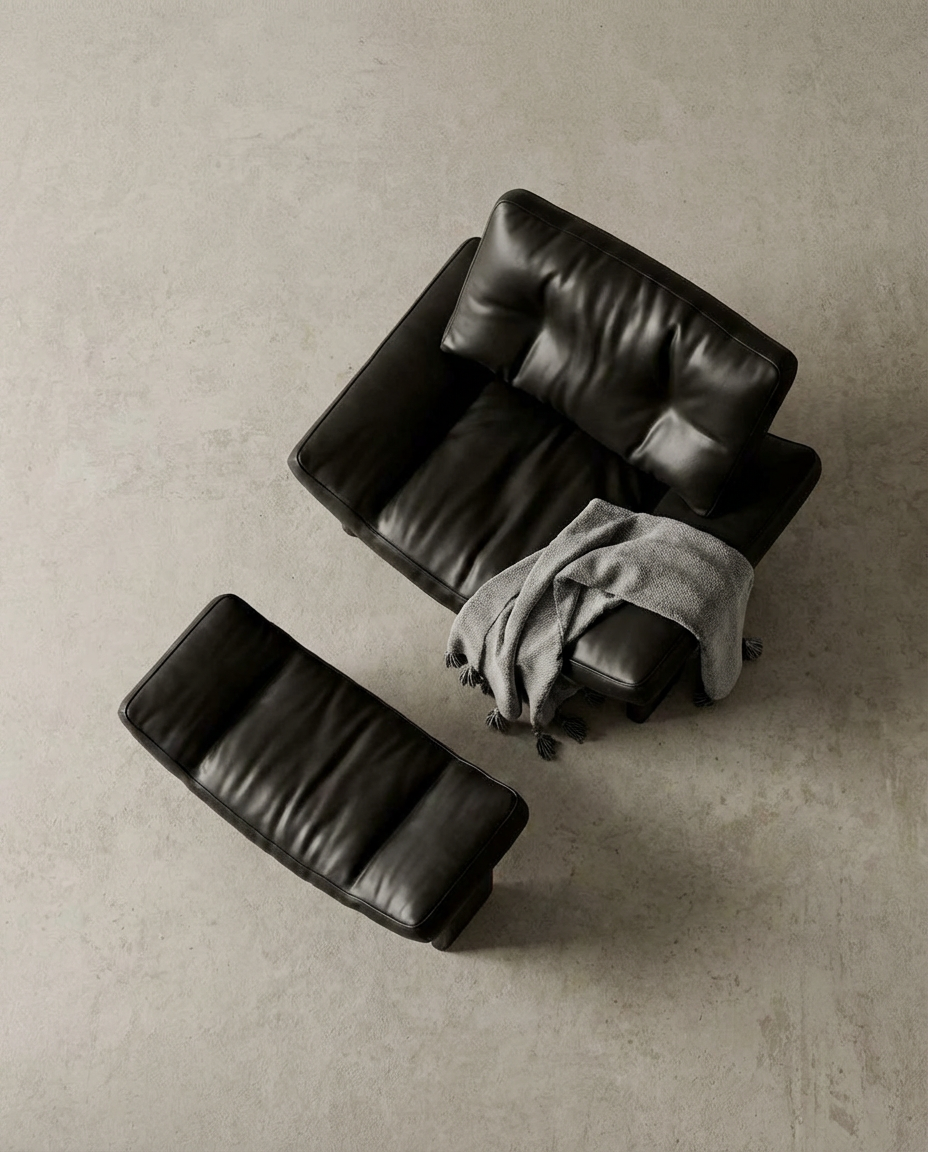 Black leather sofa and ottoman on a beige floor