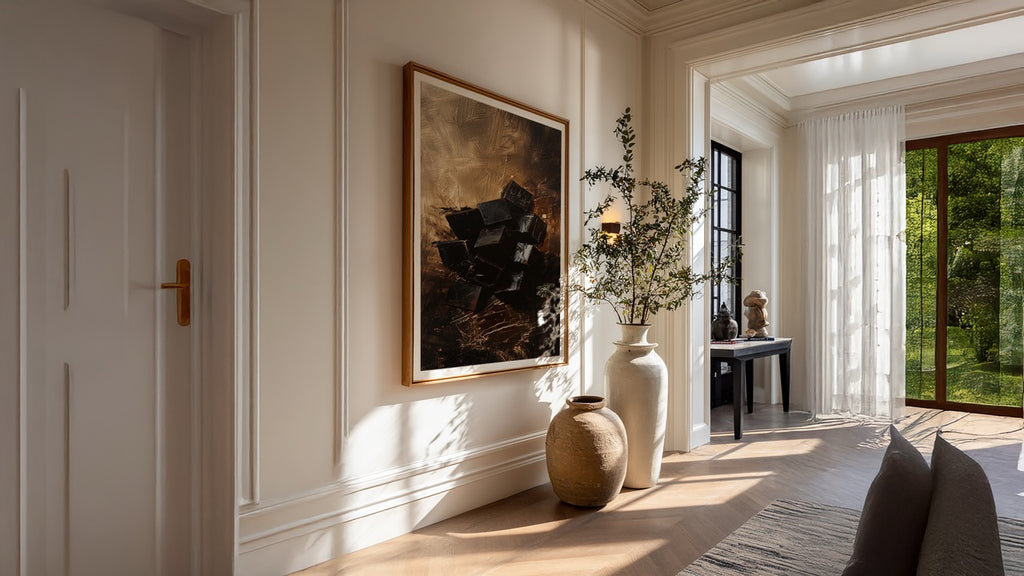 Modern interior with a painting on the wall, decorative vases, and a view of greenery outside.