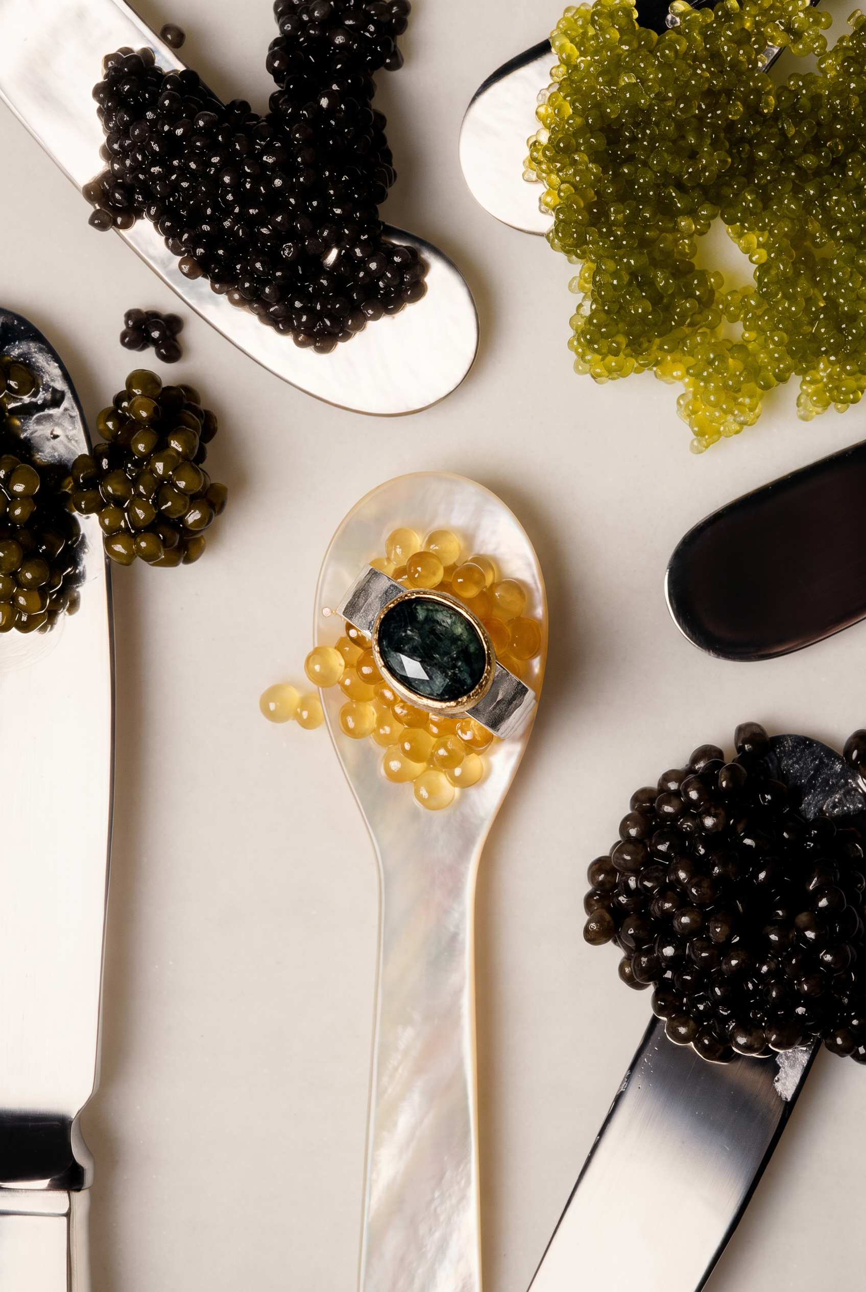 Assorted caviar on a white surface with a spoon containing yellow caviar.