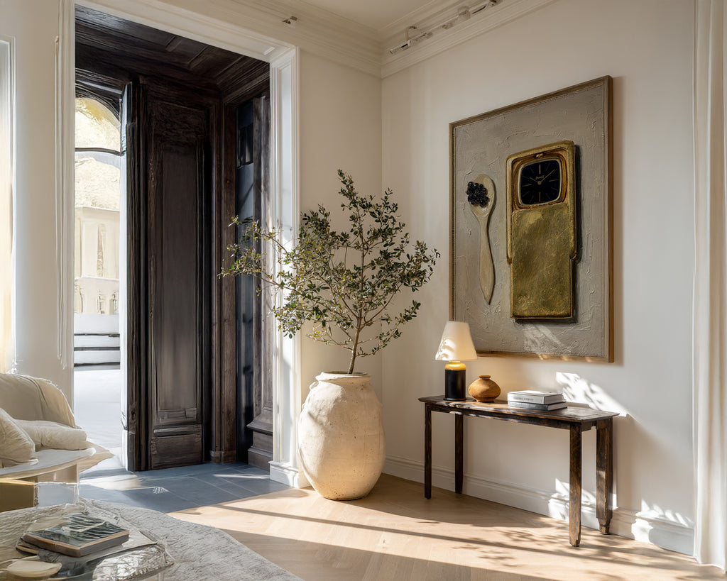 Modern interior with a vase, plant, and framed artwork on a wall.