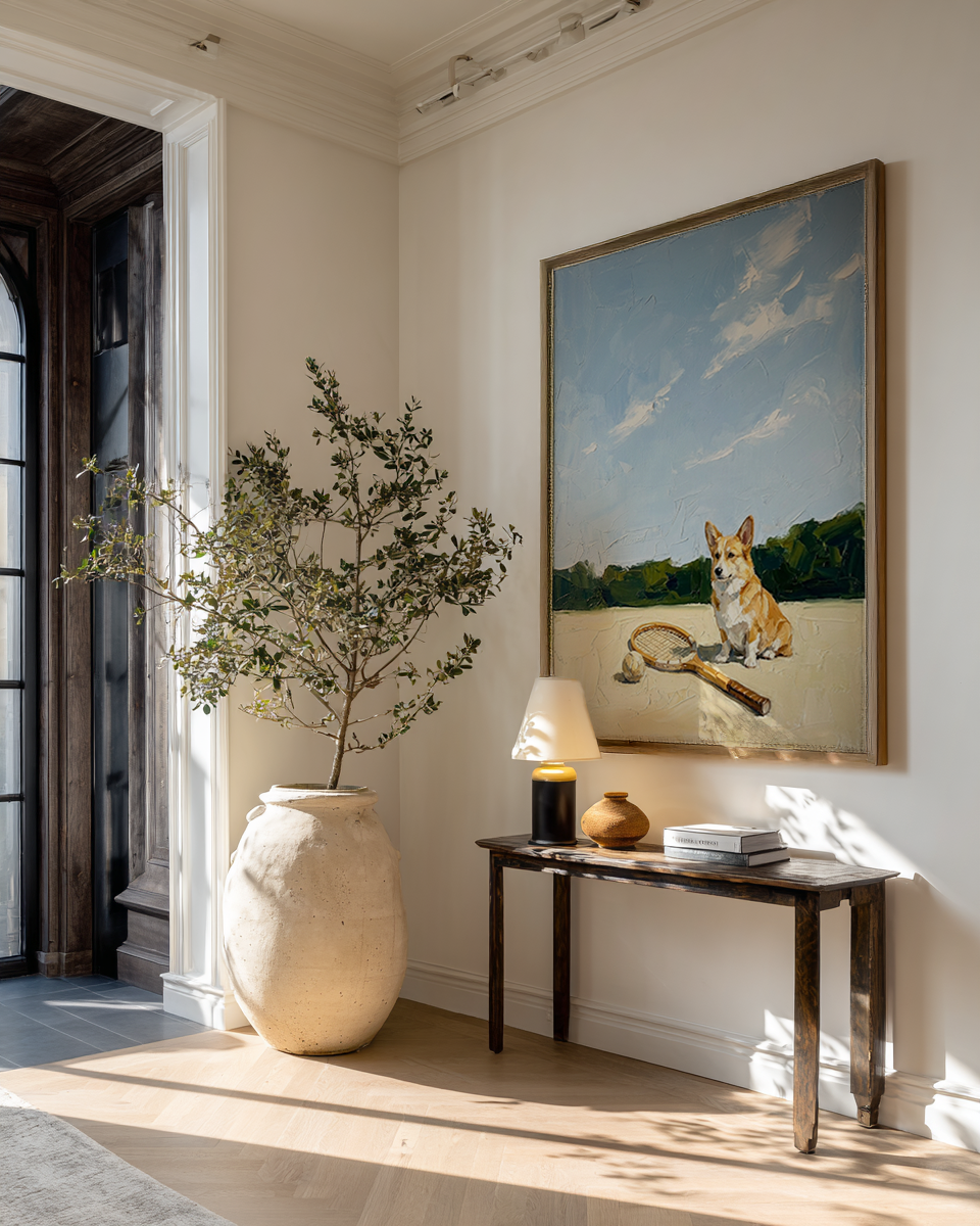 Room interior with a vase, lamp, and painting of a dog on a wall.