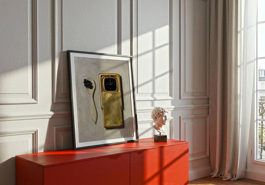 Framed artwork on a red console table with a decorative object against a white paneled wall.