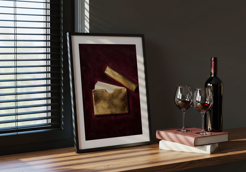 Framed artwork on a table with wine bottle and glasses.